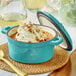 A Valor Aqua Sky enameled cast iron pot with a lid, filled with sauce and a spoon on a bowl of ice cream.