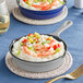 A Valor Slate Grey enameled cast iron skillet with food on a table.