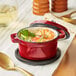 A red Valor enameled cast iron pot filled with shrimp and vegetable soup.