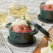Two green Valor enameled cast iron pots with covers filled with food on a table.
