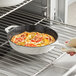 A hand using a white Valor enameled cast iron skillet to cook food in the oven.