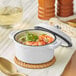 A Valor Arctic White enameled cast iron pot filled with soup with shrimp and vegetables.