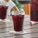A glass of DominAde grape drink with ice on a coaster.