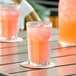 A glass of DominAde pink lemon drink on a table.