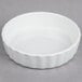 A Tuxton porcelain white souffle dish with a wavy edge.