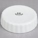 A Tuxton white porcelain round fluted dish with black text.