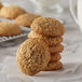 A stack of oatmeal cookies on a white table with a glass of milk.