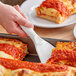 A person using an American Metalcraft flexible white spatula to serve pizza