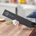 A person holding a Mercer Culinary black rectangular knife blade guard.