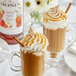 A glass mug of Monin Caramel Apple Butter syrup over coffee with whipped cream.