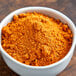 A bowl of orange powder on a wooden table.