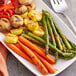 A plate of vegetables and a fork with Lawry's Seasoned Salt on a table.