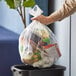 A person holding a Lavex janitorial trash bag full of trash in a trash can.