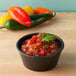 A charcoal polyethylene ramekin filled with salsa and peppers.