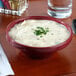 A Tuxton assorted color china wide mouth soup bowl filled with creamy soup garnished with parsley.