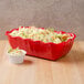A red Cambro deli crock filled with coleslaw on a salad bar counter.