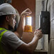 A man wearing a hard hat using a Voltec Rechargeable Portable LED Work Light.