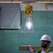 A man wearing a hard hat and holding a Voltec Metal Halide temporary area light over a piece of wood.