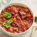 A bowl of Dei Fratelli seasoned diced tomatoes in chili with jalapenos and a spoon.