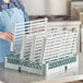 A woman holding a Regency green epoxy shelf with white polymer drop mats in it.