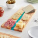 An American Metalcraft rectangular olive wood serving board with cheese and crackers on it.