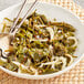 A white bowl of raw whole leaf kelp with onions and spices.