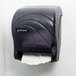 A black San Jamar paper towel dispenser on a white wall.