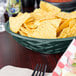 A round polyethylene basket filled with jalapeno peppers.