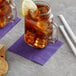 A glass mug with a lemon slice on top of a purple cocktail napkin with a lemon slice on the rim.