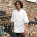 A man wearing a white Uncommon Chef Aruba Pro Vent chef coat with a mesh back.