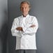 A man in a Uncommon Chef white chef coat with royal blue piping.