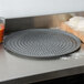 An American Metalcraft Super Perforated Hard Coat Anodized Aluminum pizza pan on a counter.