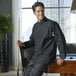 A man in a black Uncommon Chef long sleeve chef coat leaning on a pool table.