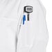A person wearing a white Uncommon Chef long sleeve chef coat with a pen in the pocket.