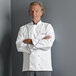 A man wearing a Uncommon Chef white chef coat with royal blue piping.