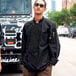 A man wearing a black Uncommon Chef long sleeve chef coat with a mesh back standing in front of a truck.