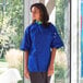 A woman wearing a Uncommon Chef blue chef coat.