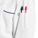 A white Uncommon Chef long sleeve chef coat with royal blue piping on the counter.