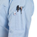 A man wearing a sky blue short sleeve chef coat with a pen in the pocket.