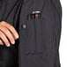 A person holding a Uncommon Chef Tempest Pro Vent long sleeve chef coat pocket with a pen.