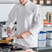 A white unisex long sleeve chef coat with a double-breasted front and chest pocket.