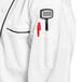 A person wearing a Uncommon Chef white chef coat with black piping and a pen in the pocket.
