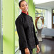 A woman wearing a black Uncommon Chef long sleeve chef coat.