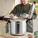 A man in a chef's uniform cooking rice in a large Zojirushi rice pot.