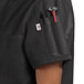 A woman wearing a black Uncommon Chef short sleeve chef coat with a red pocket.