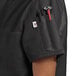 A woman wearing a black Uncommon Chef short sleeve chef coat with red trim on the pocket.
