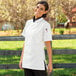 A woman wearing a white Uncommon Chef short sleeve chef coat.