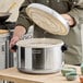 A person using a Zojirushi stainless steel rice container to cook rice.