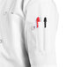 A person wearing a Uncommon Chef white chef coat with a pen in the pocket.