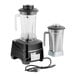 A commercial blender with a black base, a clear polycarbonate jar, and a separate stainless steel jar.